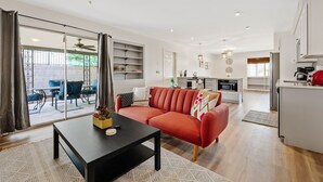 A modern living room with a red sofa, a black coffee table, and a dining area with a red chair. - Mountain Views | Hiking & Adventure (Phoenix)