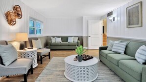 A modern living room with a grey sofa, a round coffee table with a plant, and a grey armchair. - Private Resort Home with Pool & Hot Tub (Indian Harbour Beach)