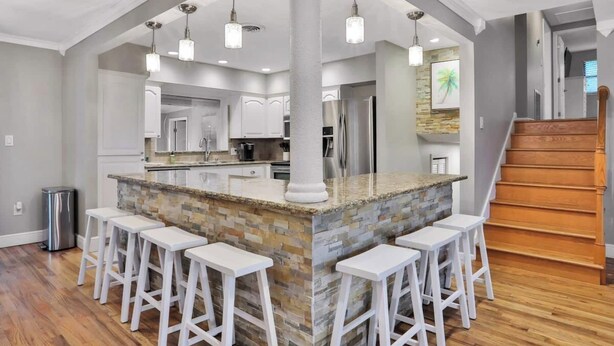 A modern kitchen with a central island, white bar stools, and pendant lighting. - Private Resort Home with Pool & Hot Tub (Indian Harbour Beach)