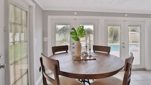A dining area with a round table, six chairs, a vase with a plant, and a candle. - Private Resort Home with Pool & Hot Tub (Indian Harbour Beach)