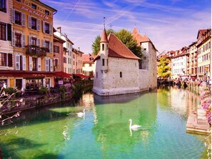A historic building with a tower and a canal with swans. - Loft Mandallaz - In the heart of the city (Annecy)
