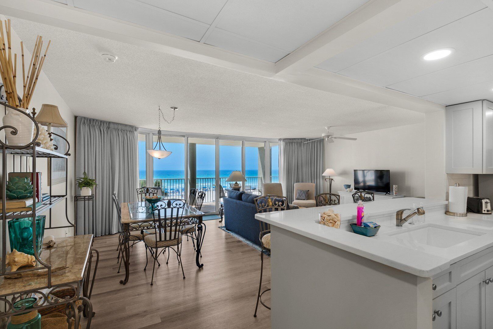 A modern hotel room with a balcony, a dining area, and a kitchen.