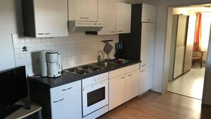 Una cuina moderna amb armaris blancs, forn integrat, cafetera i rentapelats.