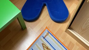 Ein blauer Sitzsack in einem Raum mit einem grünen Tisch und Holzboden.