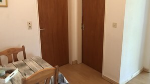 Una habitació amb una taula de fusta, dues portes de fusta i un interruptor a la paret.