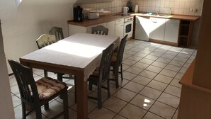 A compact kitchen with a dining area, featuring a tiled floor, a small dining table with chairs, and a window above the sink.