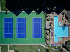 An aerial view of a tennis court complex with a pool area.