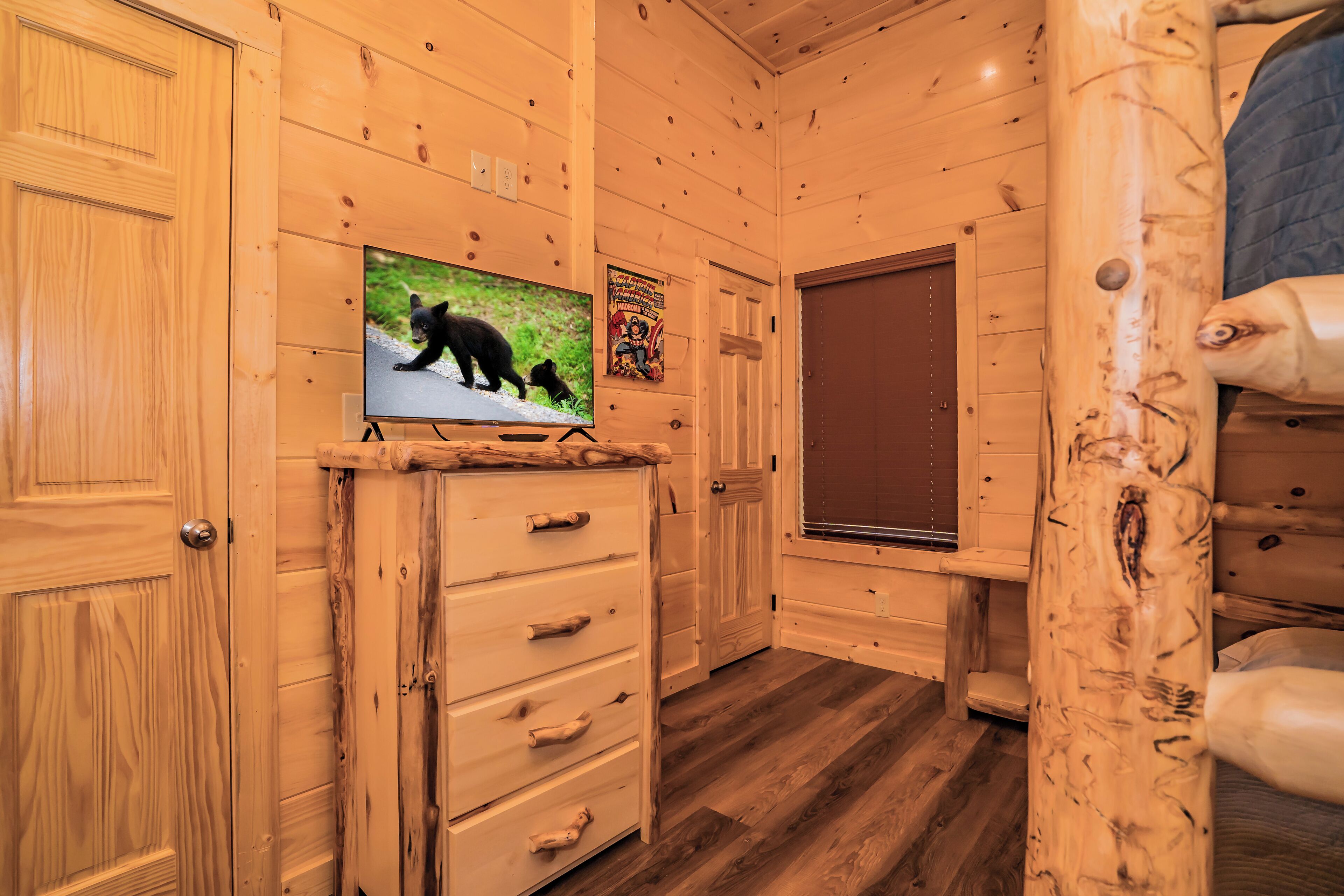 Un interior de madera con un televisor mostrando un oso, un aparador de madera y una ventana con persianas.