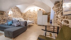 A cozy room with a stone wall, a bed, a sofa, and a table. - Vacation home Dvor by Interhome (Crikvenica)