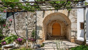 A stone archway leading to a wooden door, surrounded by a stone wall and greenery. - Vacation home Dvor by Interhome (Crikvenica)