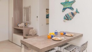 A modern kitchen with a central island, a dining table with chairs, and decorative wall art. - Lidia Capo Ceraso resort by Interhome (Porto Istana)