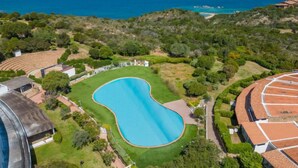 A large swimming pool surrounded by lush greenery and residential buildings. - Lidia Capo Ceraso resort by Interhome (Porto Istana)