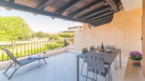 An outdoor patio with a table and chairs, a lounge chair, and a view of a green landscape. - Lidia Capo Ceraso resort by Interhome (Porto Istana)