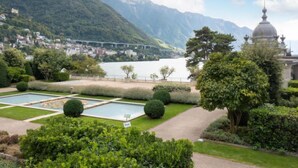 A landscaped garden with a pool, a gazebo, and a view of a lake and mountains.