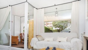 Una sala de estar acogedora con un sofá, una mesa de centro con pasteles y vistas a la vegetación.