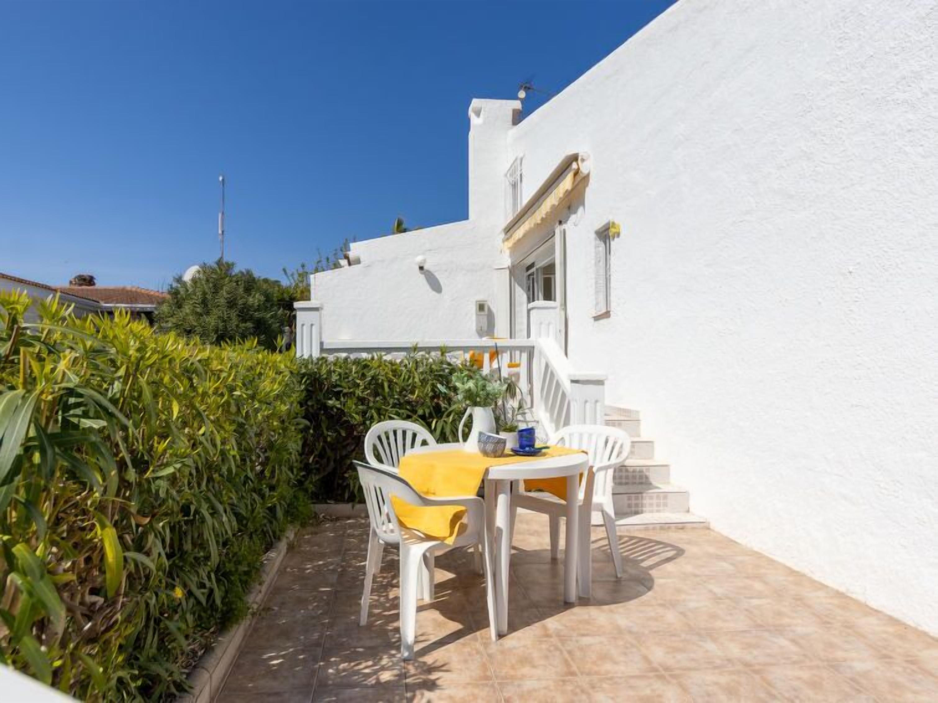 A white building with a yellow table and chairs outside.