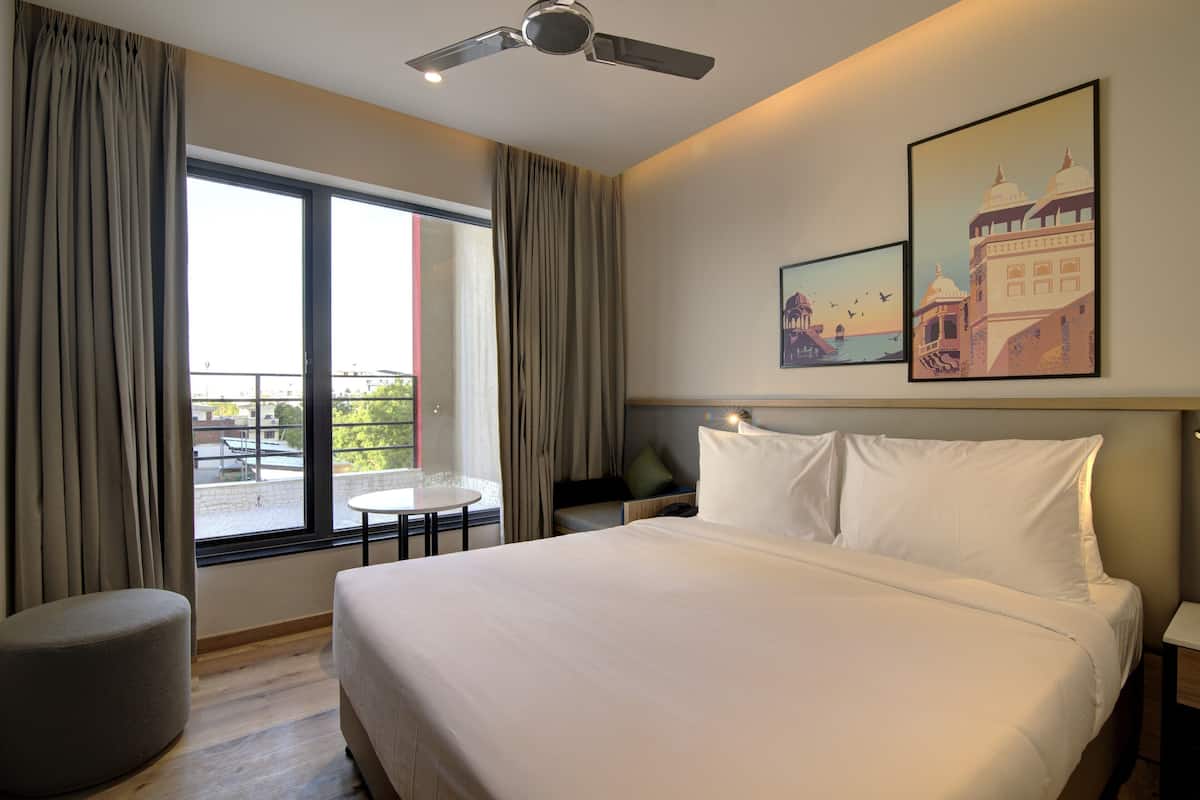 Ein Hotelzimmer mit einem Bett, einem runden Tisch, einem Deckenventilator und großen Fenstern.