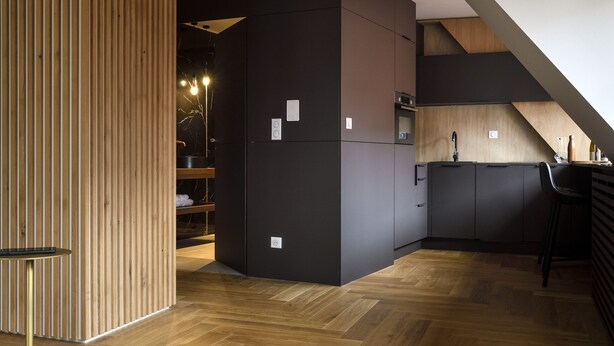 Een moderne keuken met houten balken, een visgraatvloer en een zwarte koelkast.