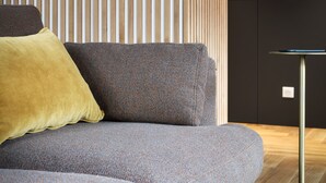 Een moderne woonkamer met een grijze bank, een geel kussen en een ronde tafel met een metalen voet.