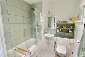 Une salle de bain moderne avec une douche à parois de verre, une baignoire blanche, un lavabo et des toilettes.