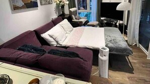 Un salon moderne comprenant un canapé, un lit, un téléviseur et un coin repas avec une table et des bougies.