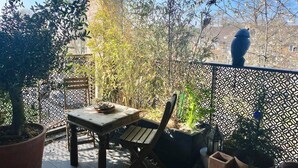 Un balcon agrémenté d’une table et de chaises, entouré de plantes en pot et d’une clôture décorative.