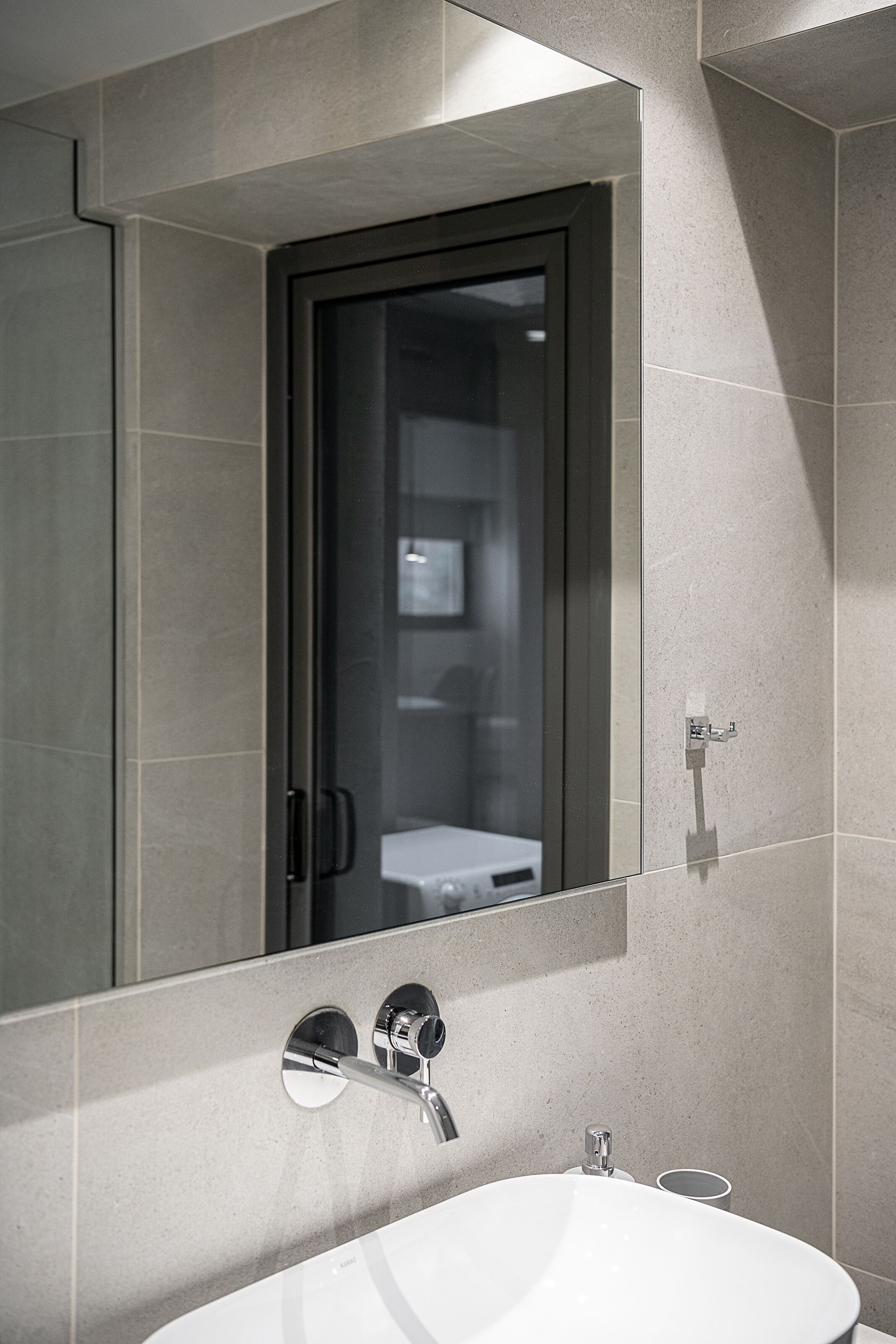 A modern bathroom with a large mirror, a sink, and a shower area.