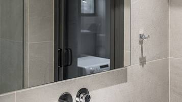 A modern bathroom with a large mirror, a sink, and a shower area.