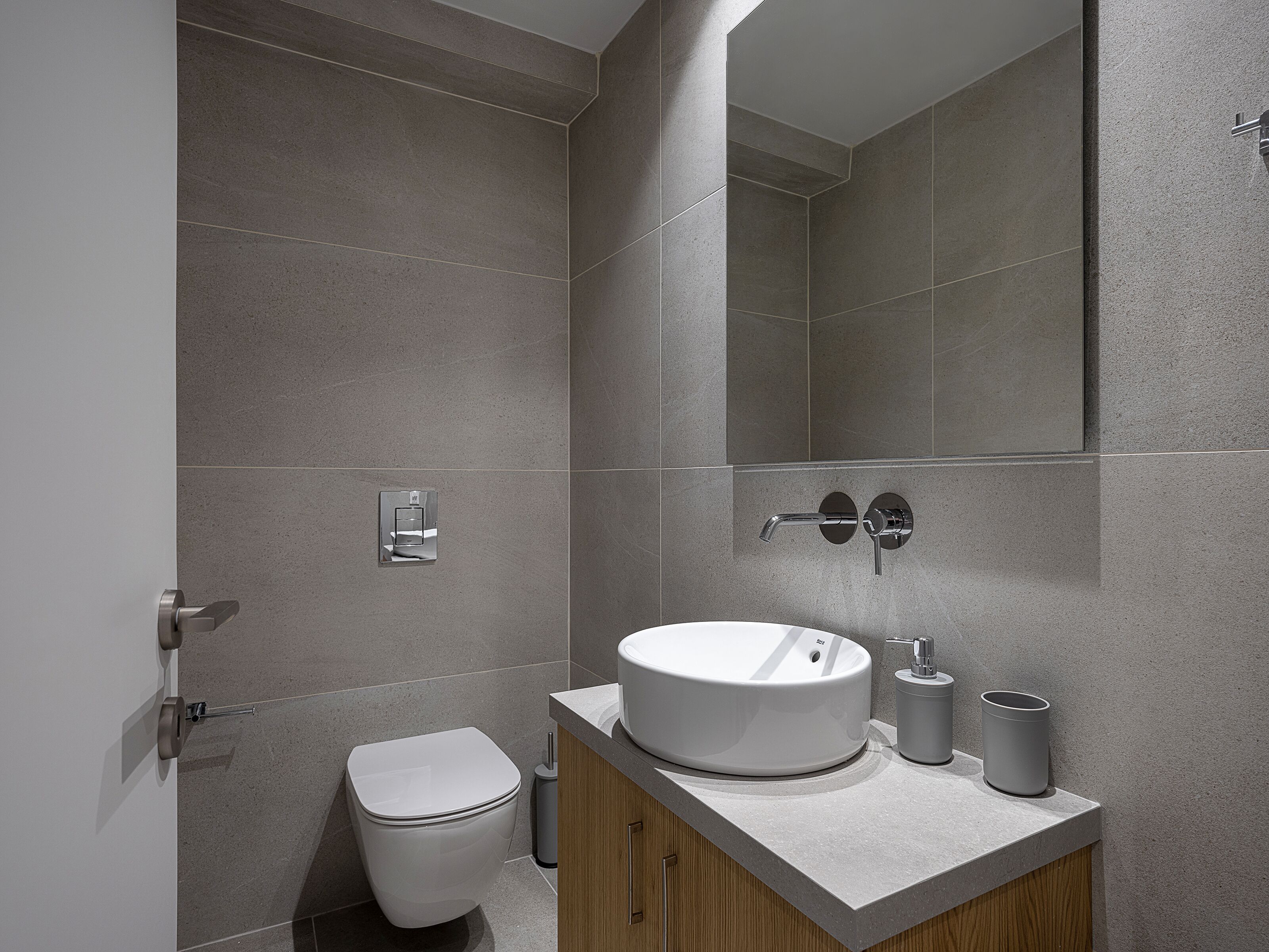 Un bagno moderno con un lavandino bianco, un water e uno specchio.