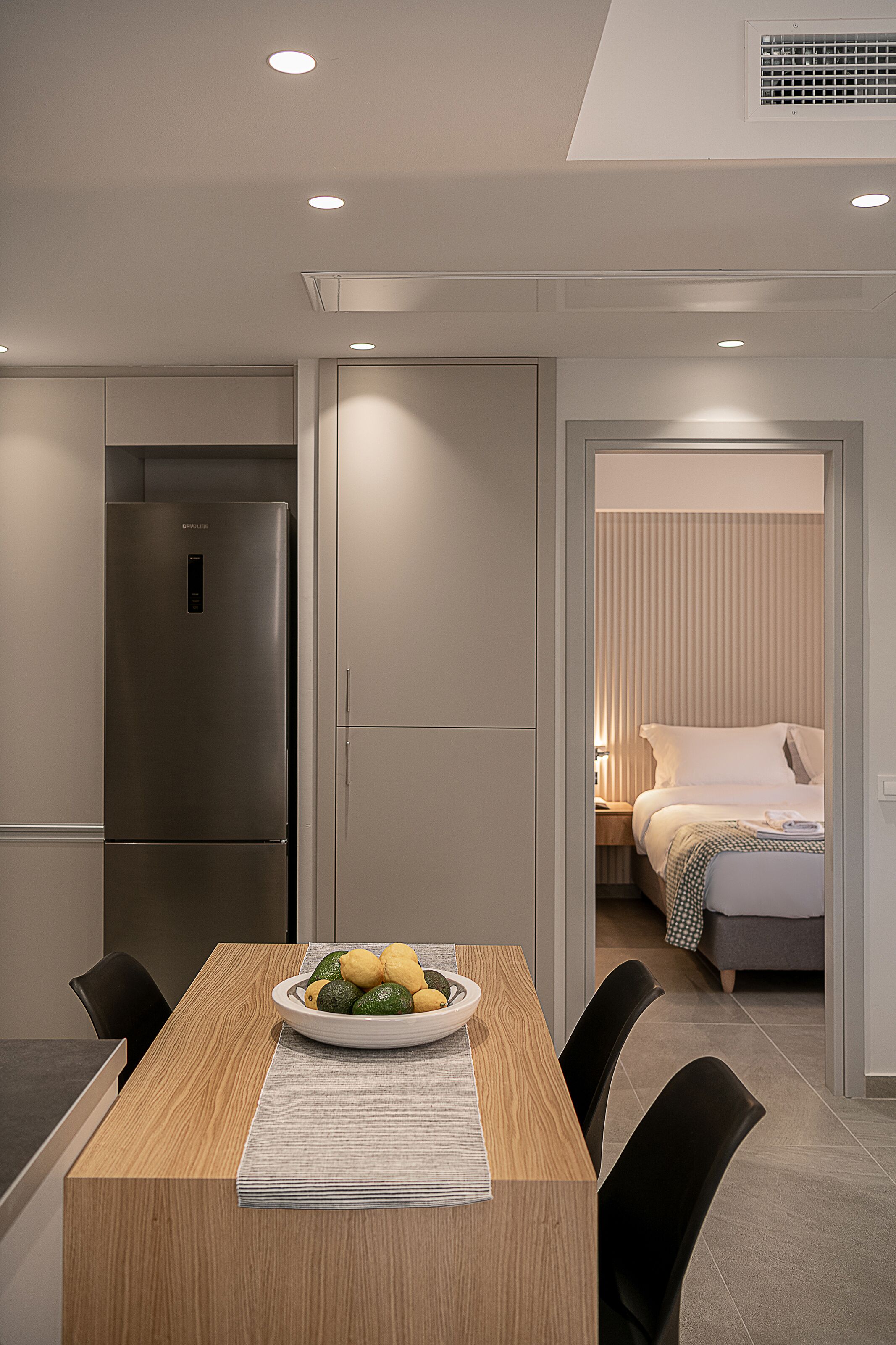 Una habitación de hotel moderna con cama, mesita de noche y zona de comedor con mesa y sillas.