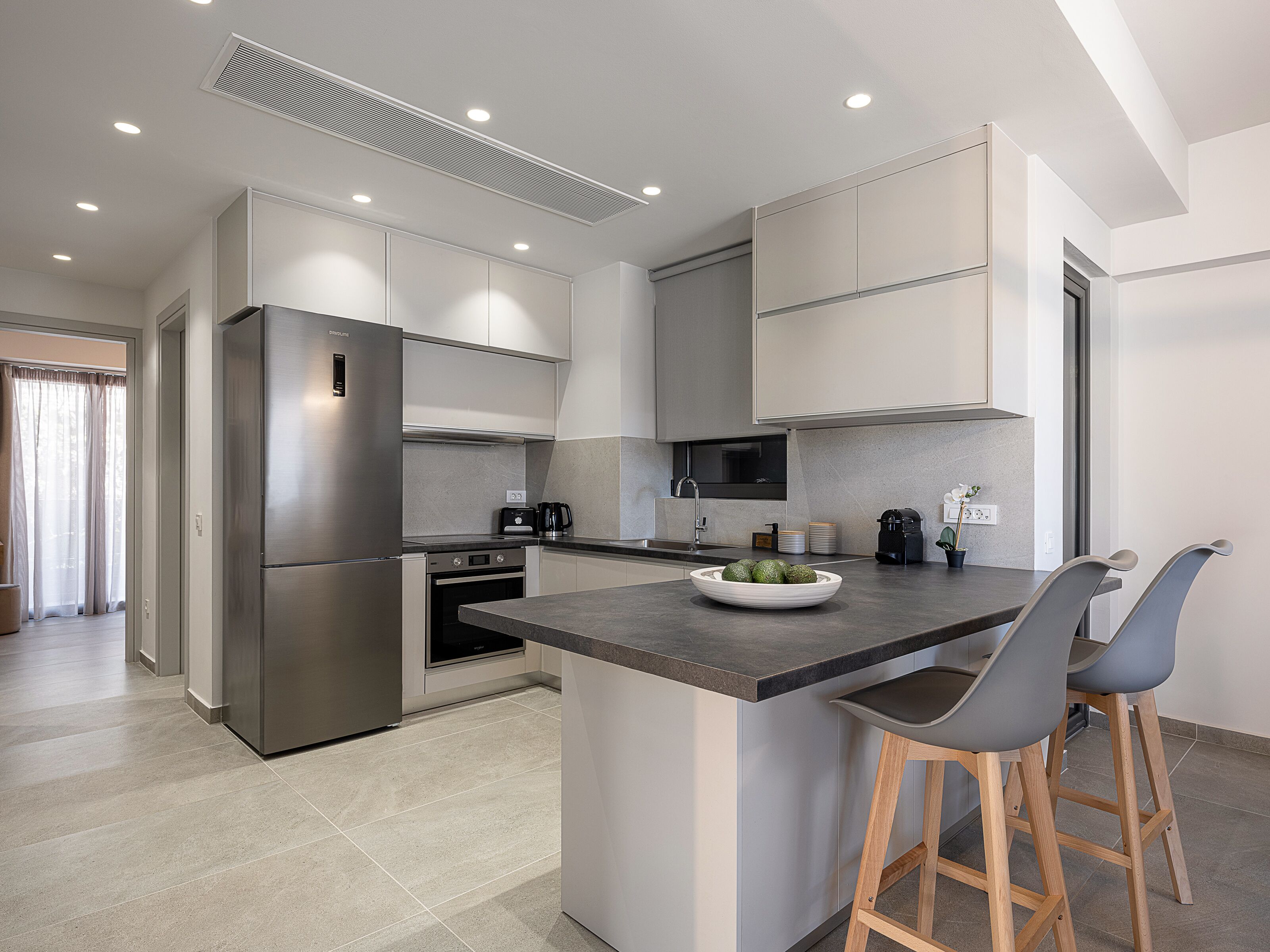 A modern kitchen with a built-in island, stainless steel appliances, and wooden bar stools.