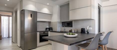 A modern kitchen with a built-in island, stainless steel appliances, and wooden bar stools.