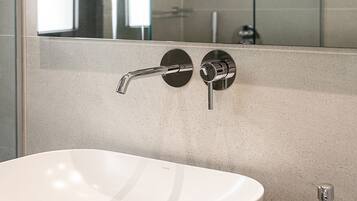 A bathroom with a white sink, a mirror, and a glass shower enclosure.