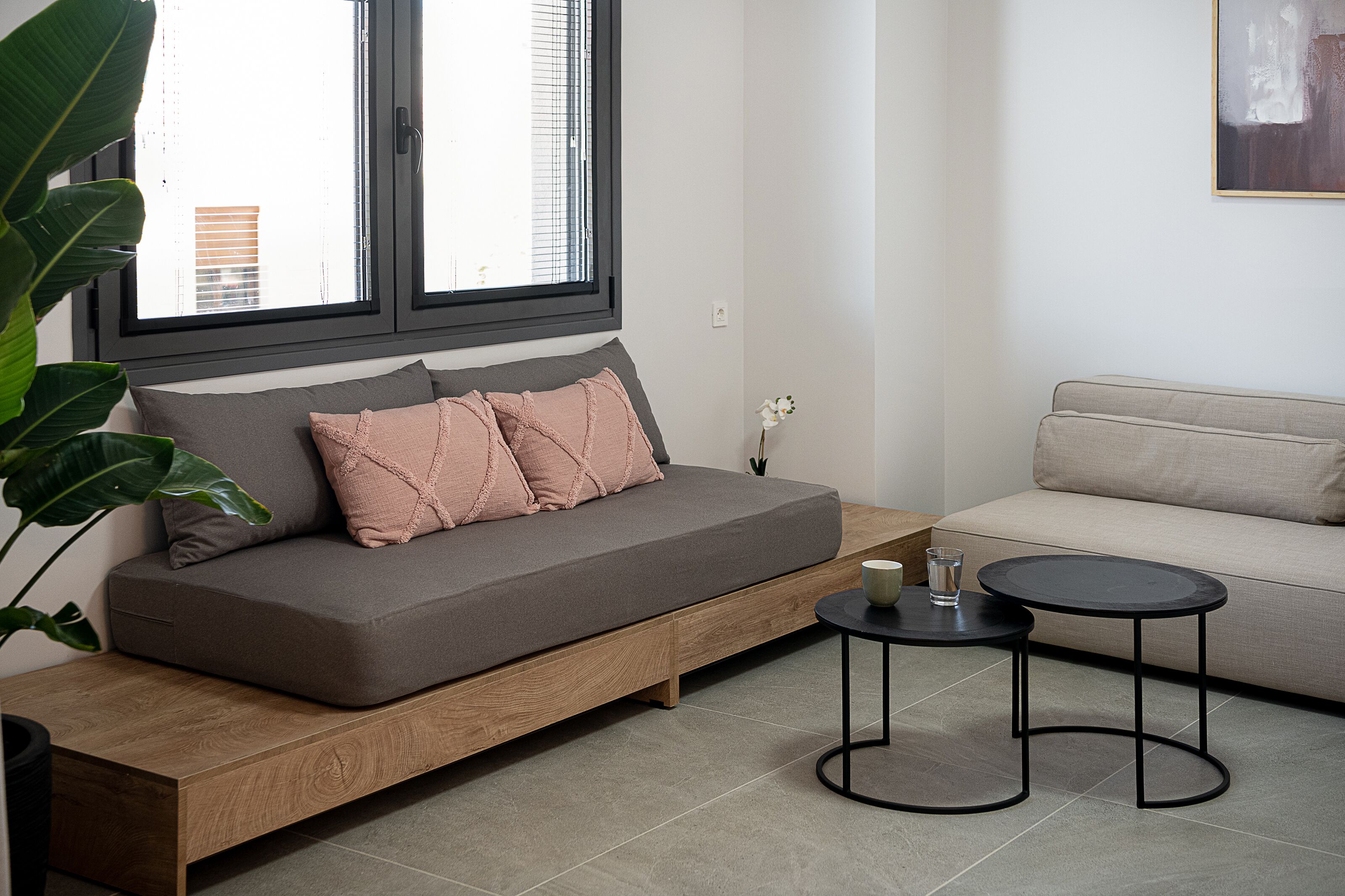 Una sala de estar moderna con un sofá gris, un banco de madera y una mesa redonda negra.