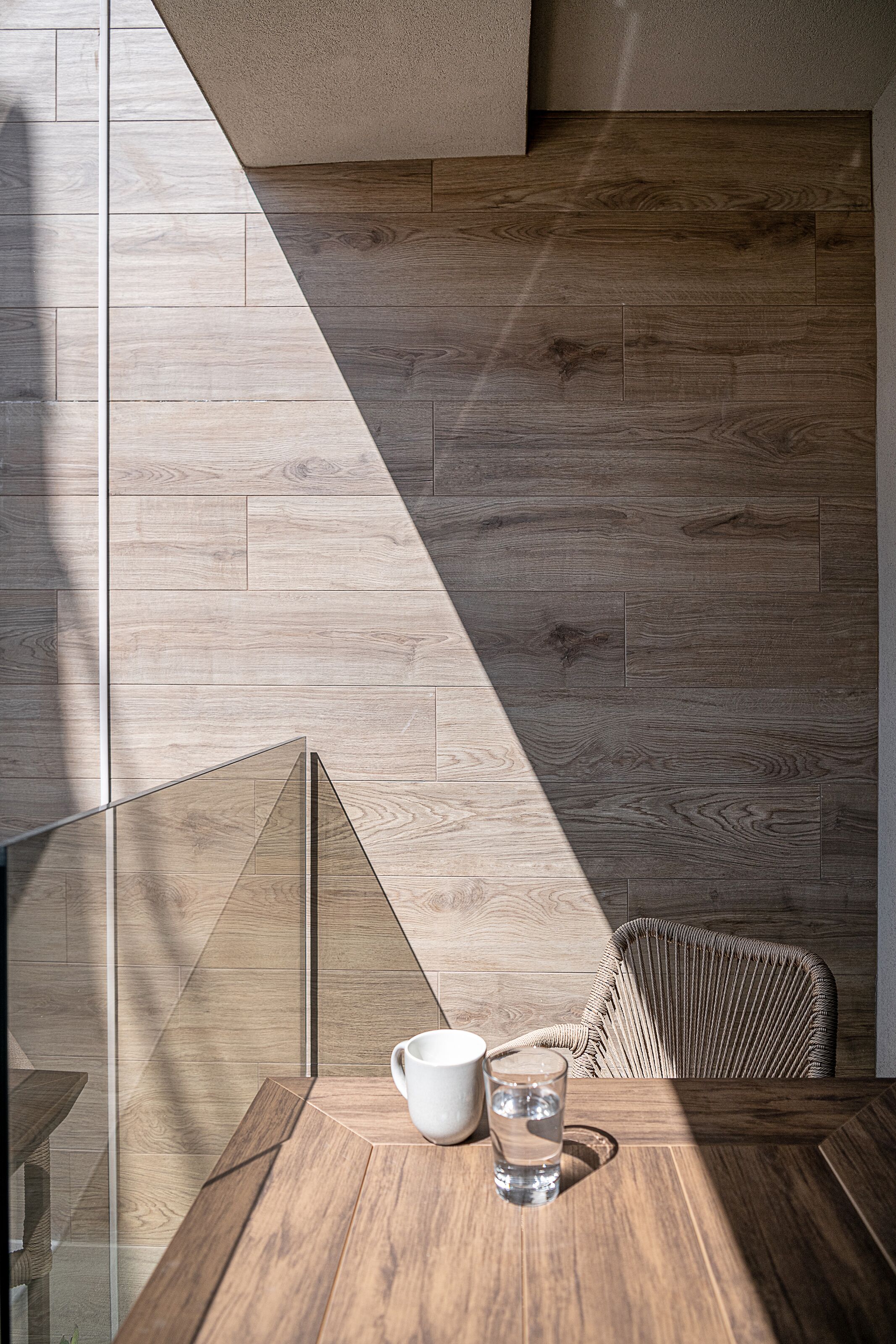 Un interior moderno con una mesa de madera, una taza blanca y un vaso de agua.