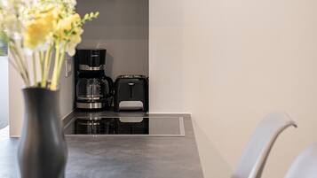 A modern kitchen with a coffee maker, toaster, and a vase with flowers on the counter.