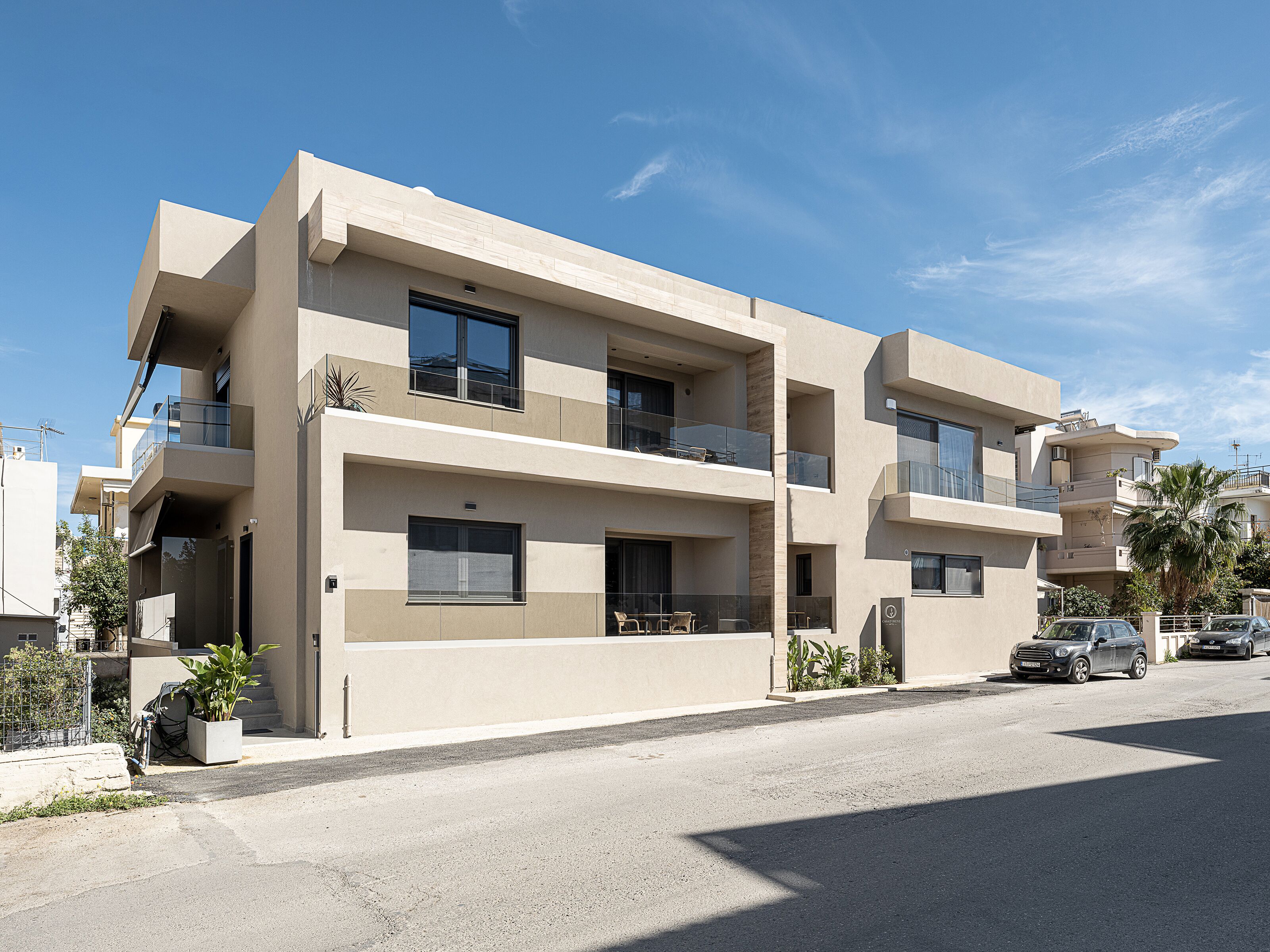 A modern multi-story residential building with balconies, large windows, and a clean, minimalist design.
