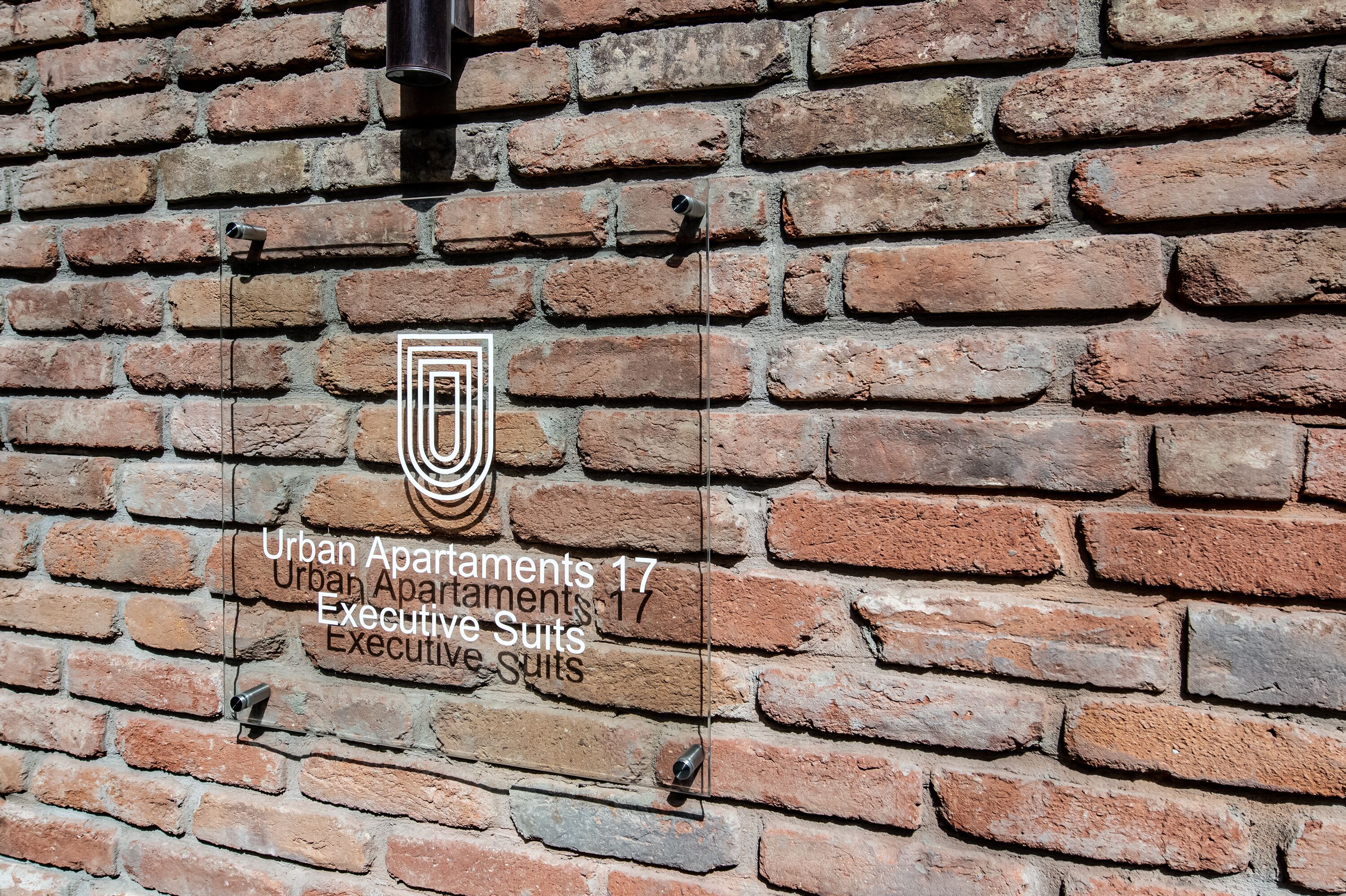 A brick wall with a sign indicating "Urban Apartments 17 Executive Suites."