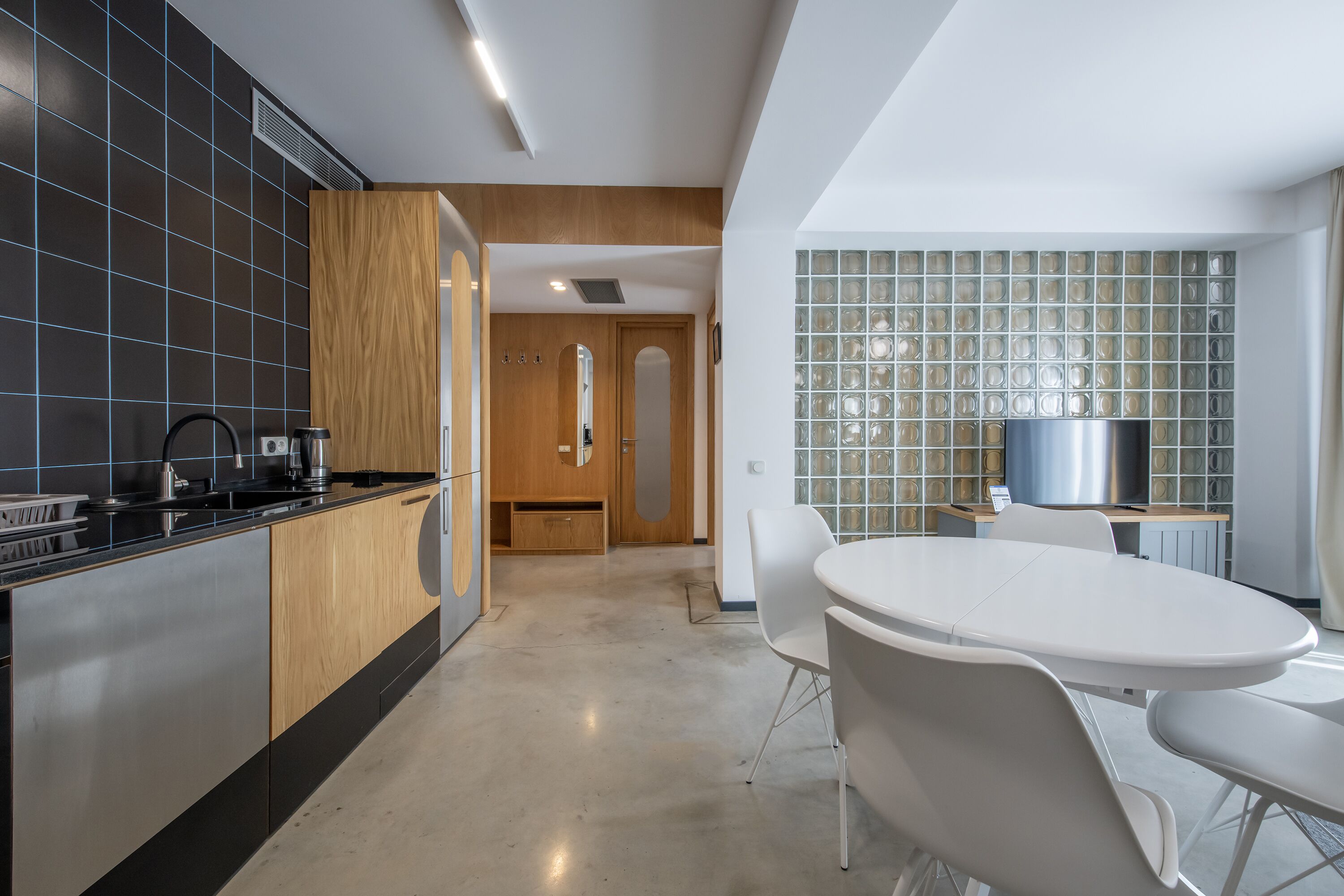 A modern kitchen with a central island, white chairs, and a dining table.
