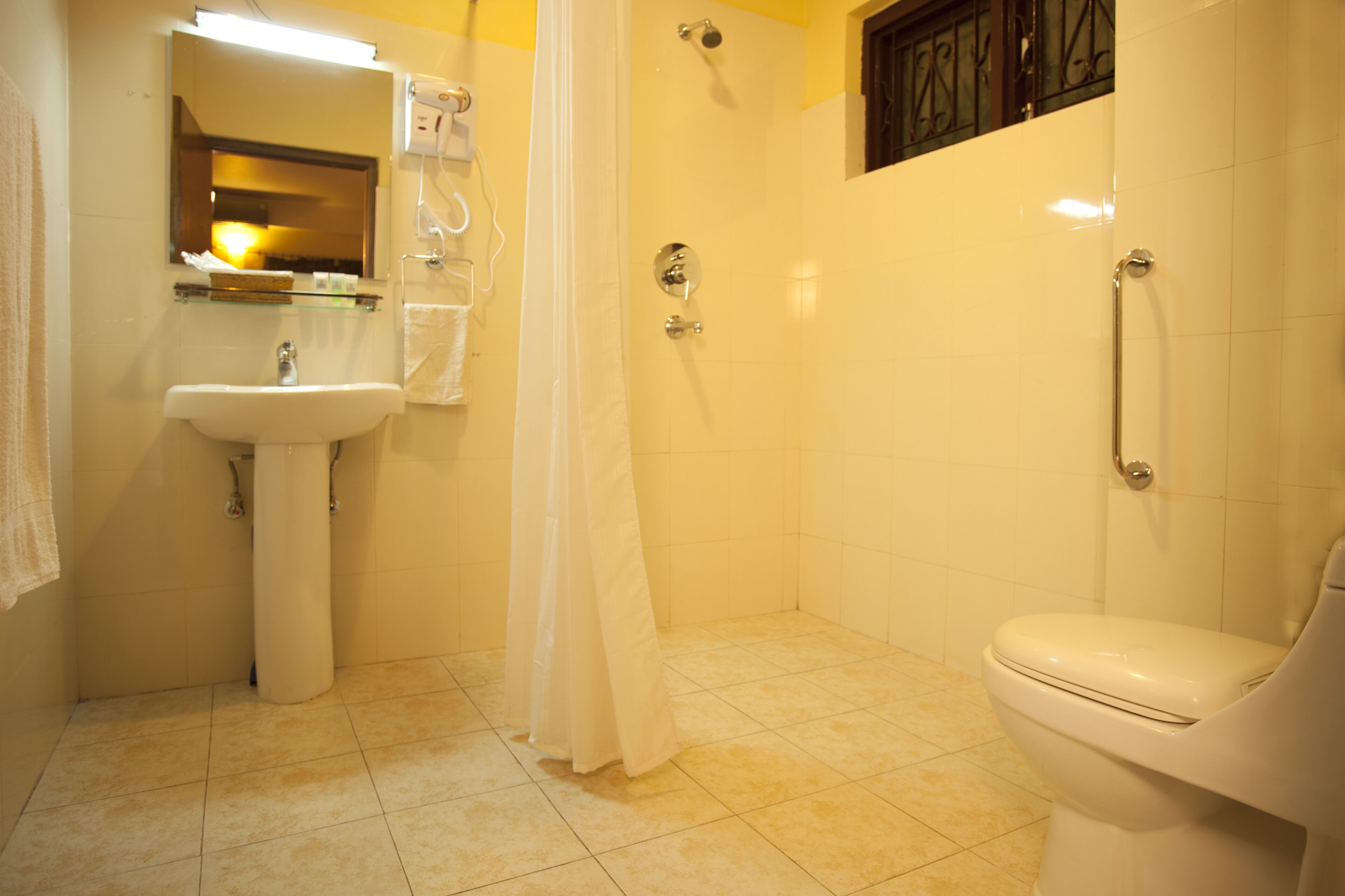 A bathroom with a sink, toilet, shower, and a mirror.