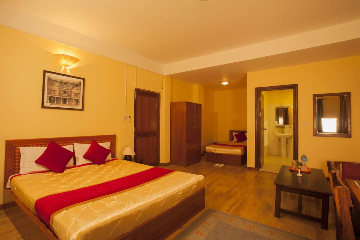 Una habitación de hotel con cama, escritorio, silla, baño y espejo.