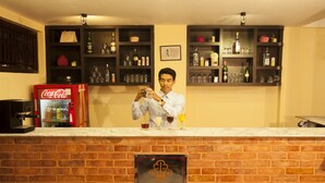 A bar area with a Coca-Cola machine, shelves with bottles and glasses, and a sign for the Royal Astoria Hotel in Kathmandu, Nepal. - Royal Astoria Hotel (Burhanilkantha)