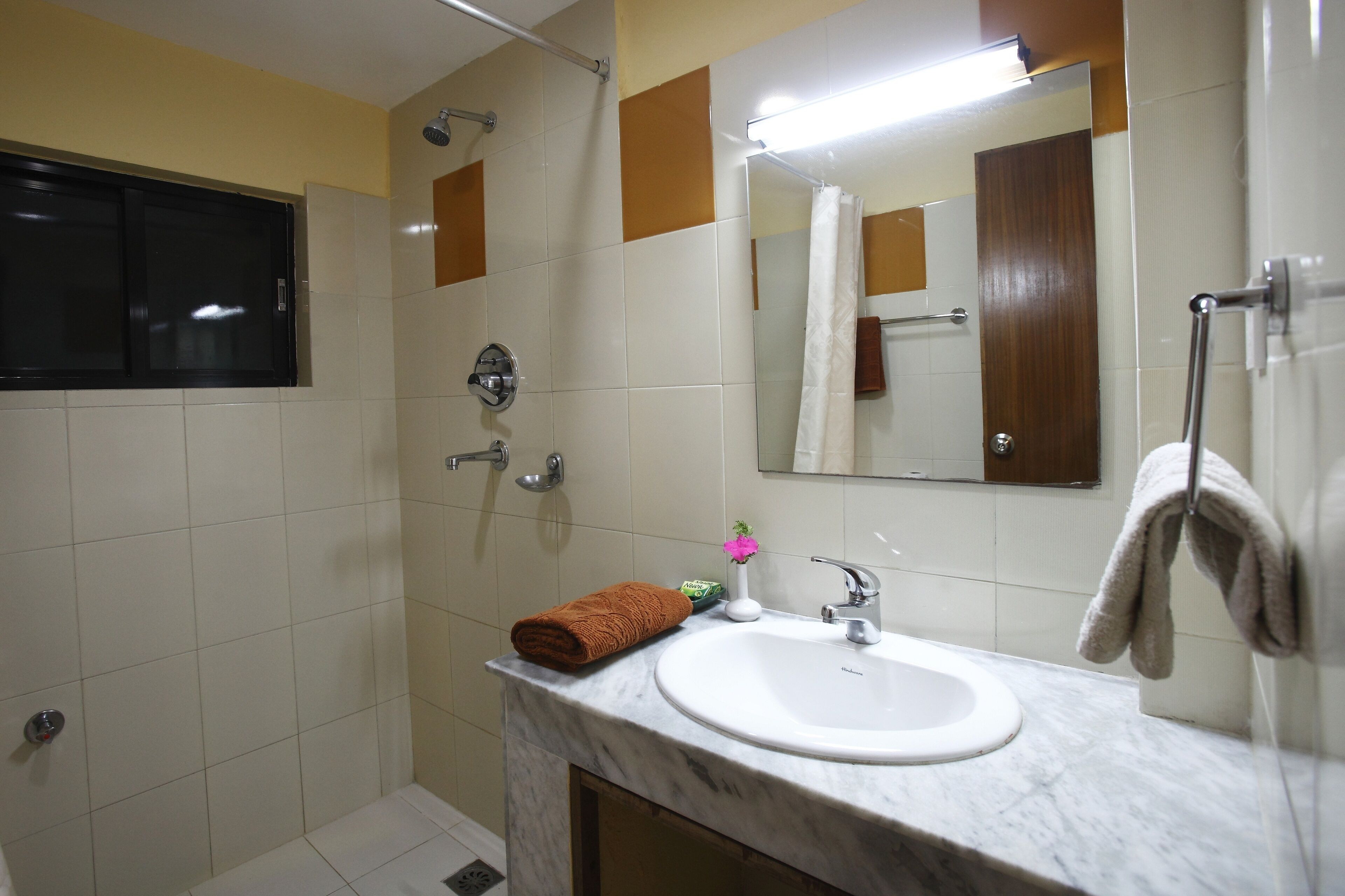 A bathroom with a white sink, a mirror, a shower, and a towel rack.