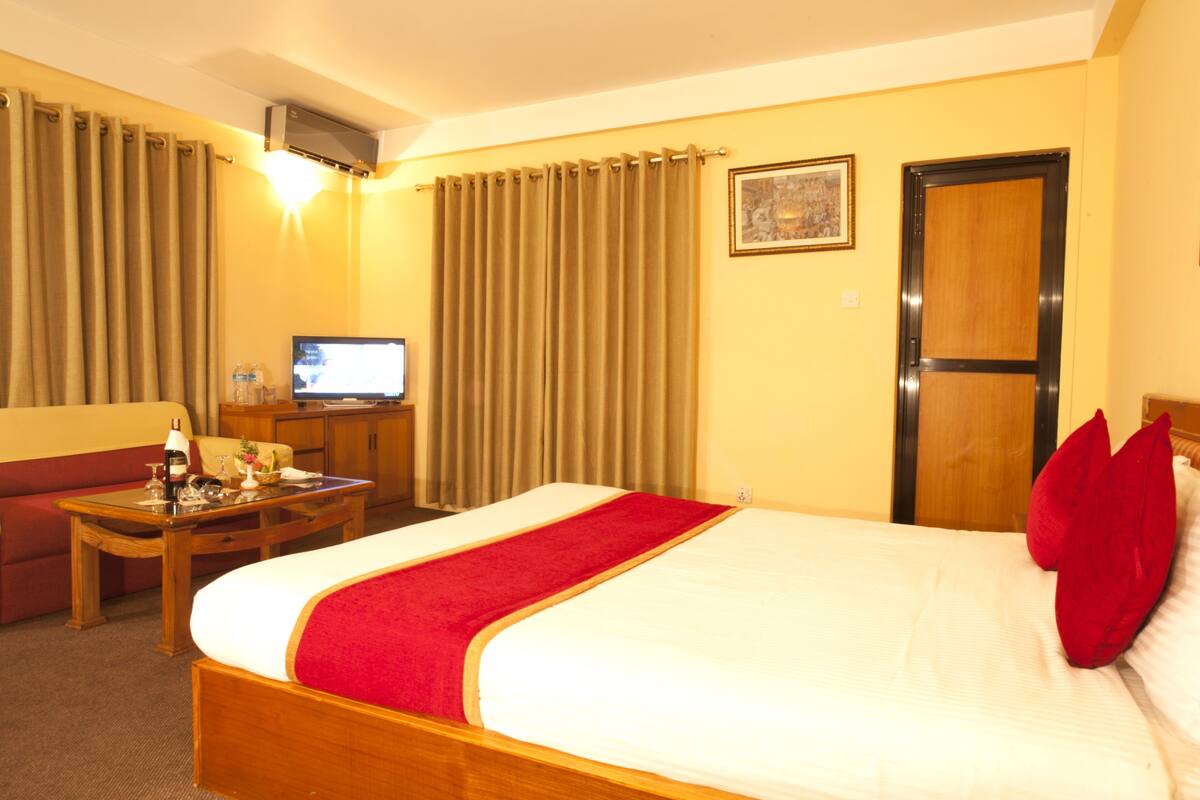 Una habitación de hotel con cama, escritorio, televisor y sofá.