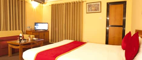 A hotel room with a bed, a desk, a television, and a sofa.