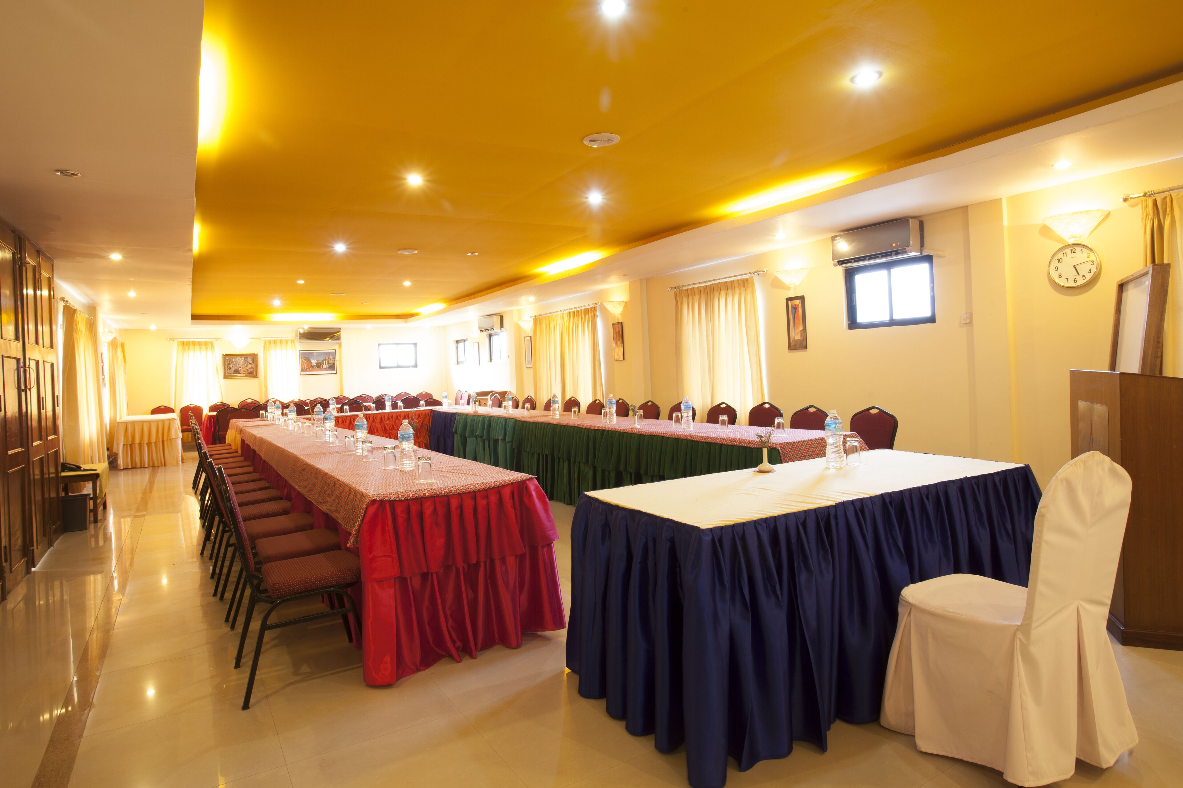 A conference room with long tables, chairs, and a clock on the wall.