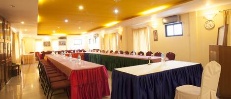 A conference room with long tables, chairs, and a clock on the wall.