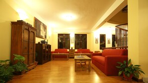 A spacious living room with wooden flooring, a red sofa, a coffee table, and a wooden cabinet. - Royal Astoria Hotel (Burhanilkantha)