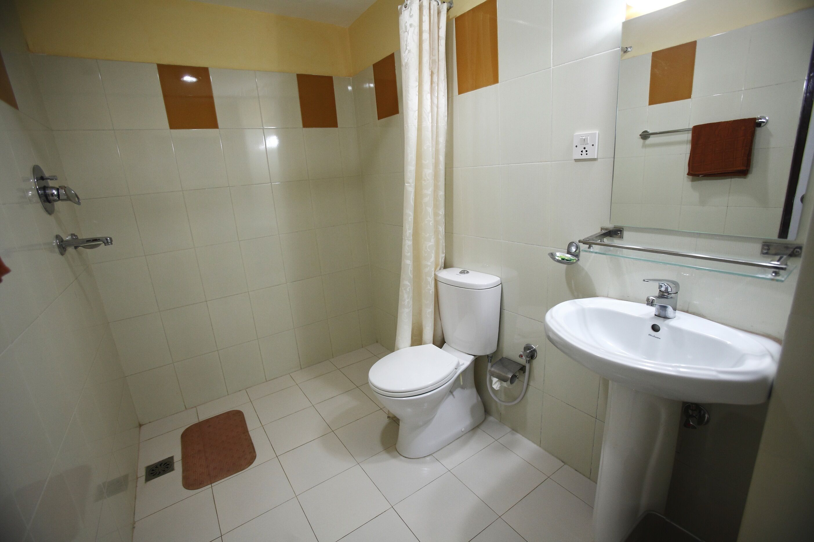 A bathroom with a toilet, sink, shower, and a mirror.