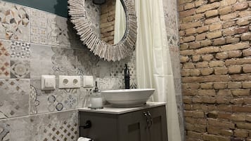 Casa de banho com lavatório, espelho e azulejos estampados.